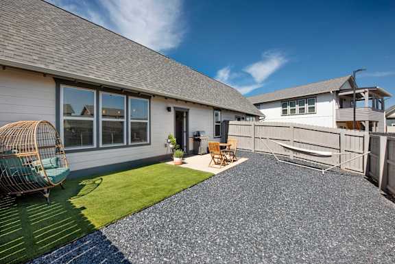 A house with a grey roof and a white exterior is shown with a patio area in front at The Cottages at Old Monrovia Apartment , Alabama
