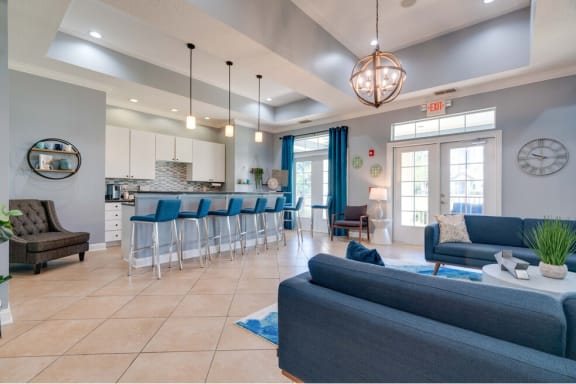 newly renovated clubhouse with blue couches and chairs and a kitchen with a breakfast bar at Magnolia Village Apartments, Jacksonville, Florida