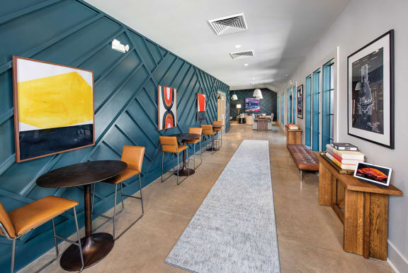 a lobby with tables and chairs and a blue wall with paintings at The Cottages at Old Monrovia Apartment , Huntsville, AL