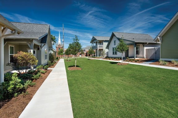 a green lawn in front of a row of houses at The Cottages at Old Monrovia Apartment , Huntsville