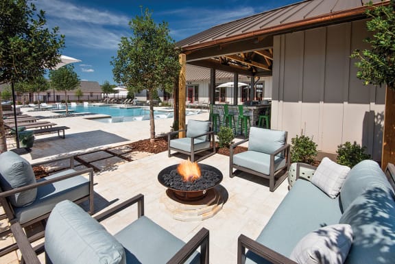 a fire pit on a patio next to a swimming pool at The Cottages at Old Monrovia Apartment , Huntsville, AL
