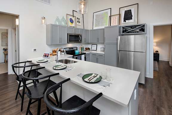 A kitchen with a white counter top and black chairs at The Cottages at Old Monrovia Apartment , Huntsville, 35806
