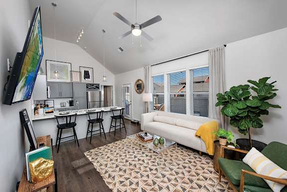 A living room with a white couch, a green chair, and a patterned rug at The Cottages at Old Monrovia Apartment , Huntsville, Alabama