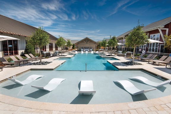 a large swimming pool with lounge chairs and umbrellas at The Cottages at Old Monrovia Apartment , Alabama, 35806