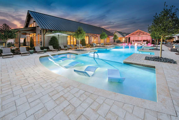 a large swimming pool with lounge chairs and a building in the background at The Cottages at Old Monrovia Apartment , Huntsville