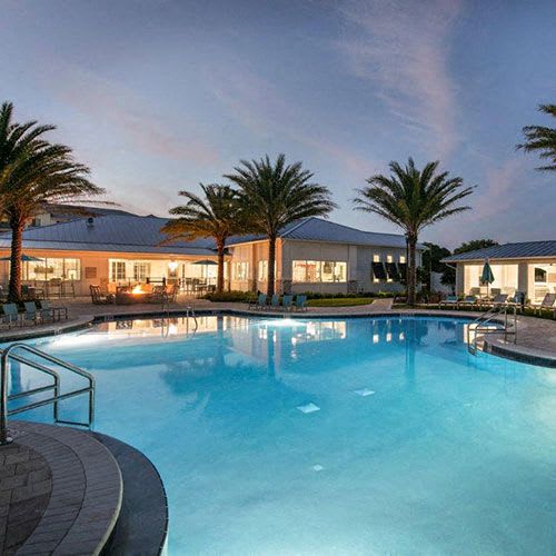 a large swimming pool with palm trees next to a building