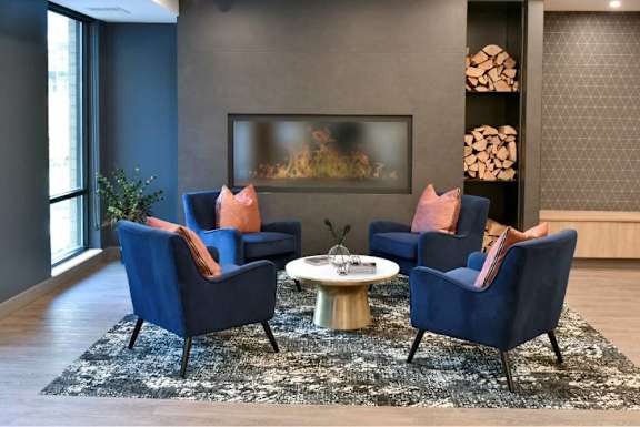 A living room with a fireplace and blue chairs. at The Arlow on Kellog, St. Paul, MN, 55102