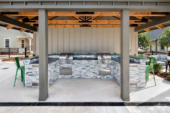 a covered patio with a barbecue grill and chairs at The Cottages at Old Monrovia Apartment , Alabama, 35806