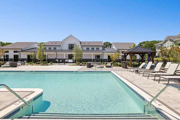 A swimming pool in front of a house with a gazebo at The Arboretum Apartments, Farmingville, New York