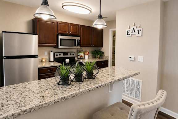 A kitchen with granite countertops and a stainless steel refrigerator.