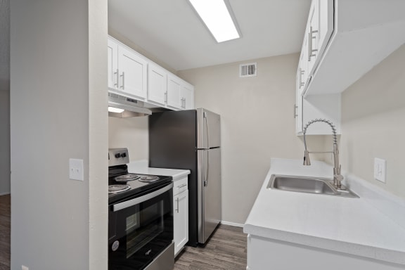 a kitchen with white cabinets and black appliances and a stainless steel refrigerator