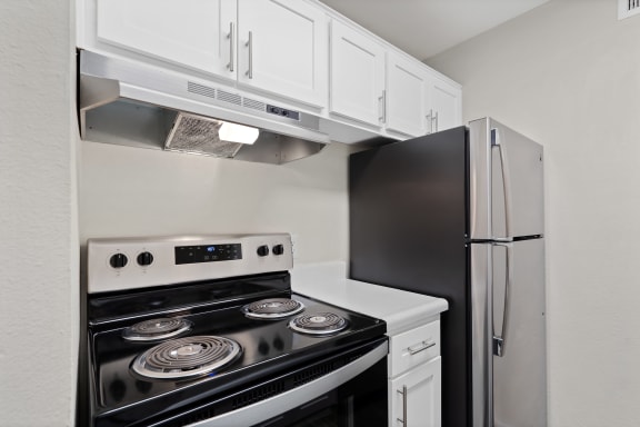 a kitchen with white cabinets and black appliances and a refrigerator