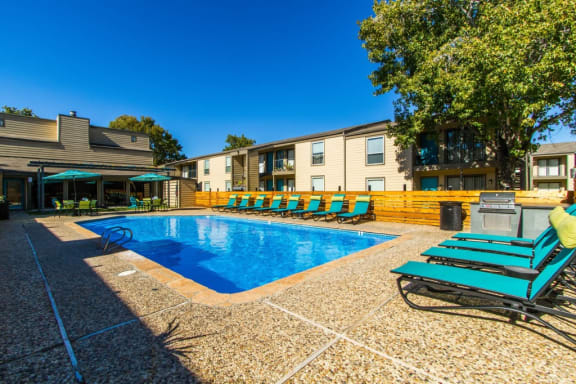 our apartments have a large swimming pool with chairs at Sundance and Sausalito Apartments, College Station, TX