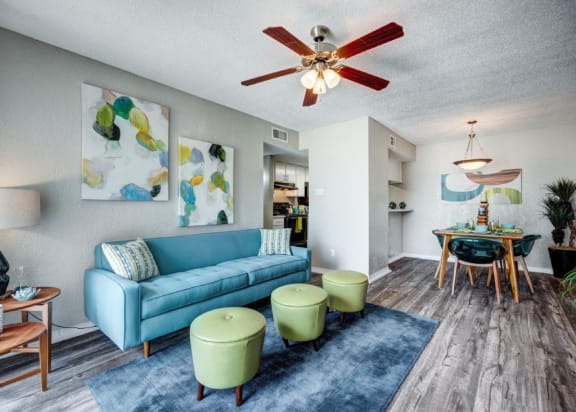 Living room with a blue couch and a ceiling fan at Sundance and Sausalito Apartments, Texas, 77840