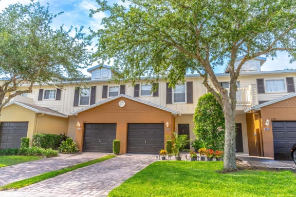 a large house with two garages and trees in front of it