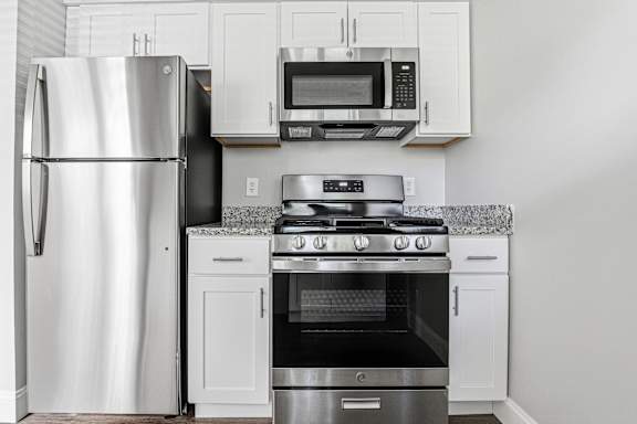 A kitchen with a stainless steel refrigerator, an oven, and a microwave above the stove.