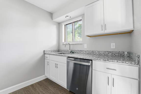 A kitchen with white cabinets and a granite countertop.