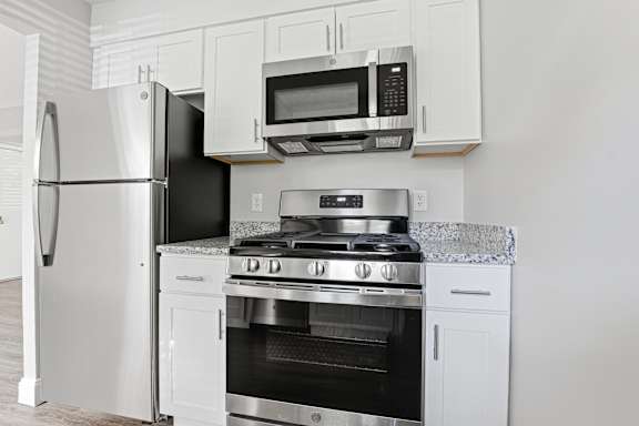 A modern kitchen with a stainless steel refrigerator, microwave, and oven.