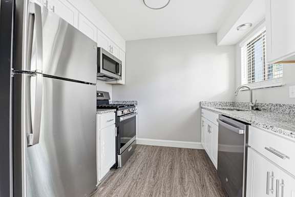 A kitchen with a stainless steel refrigerator and white cabinets.