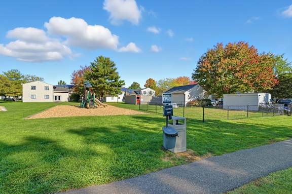 A park with a trash can and a pathway.
