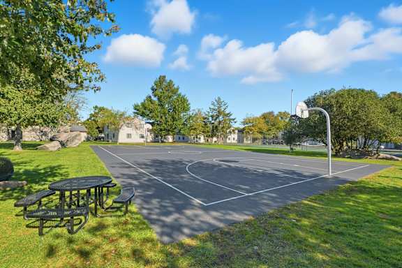 A basketball court with a basketball hoop and a picnic table.