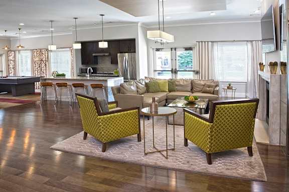 A modern living room with a kitchen in the background at Axis at Lakeshore Apartments, Bridgewater