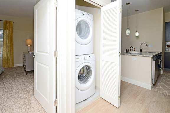 A white door is open to a laundry room and a kitchen at Axis at Lakeshore Apartments, Massachusetts