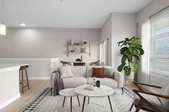 A living room with a white couch, a coffee table, and a plant.