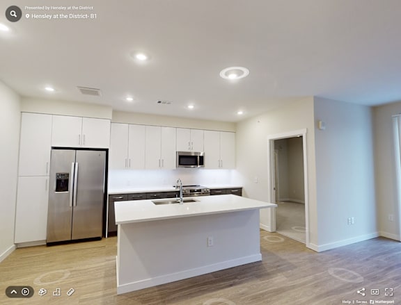 A modern kitchen with white cabinets and a stainless steel refrigerator.