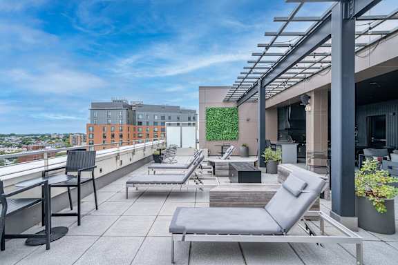 A rooftop patio with grey chairs and tables.