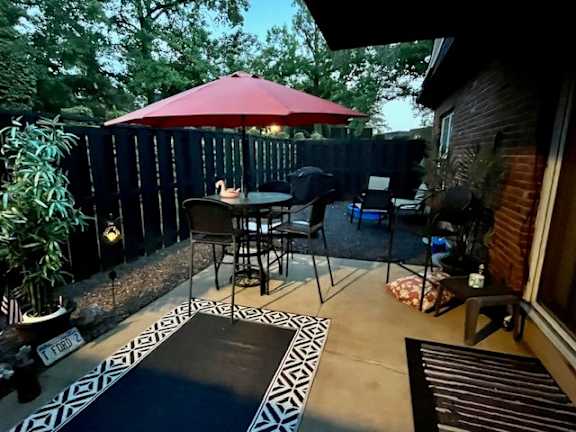 a patio with a table and a red umbrella