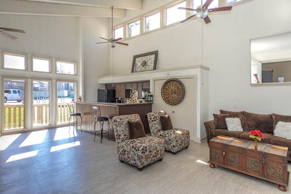 A living room with a brown couch, a chair with a floral pattern, and a wooden coffee table.