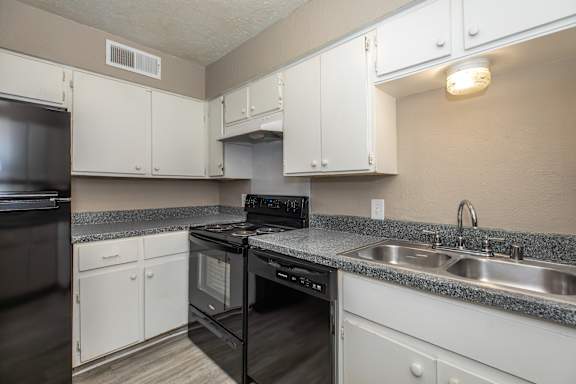 A kitchen with white cabinets and a black oven.
