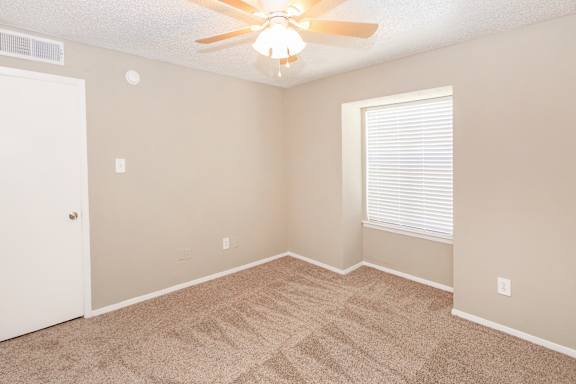 A room with a ceiling fan and carpeted floor.