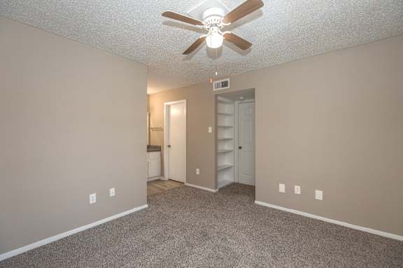 A room with a ceiling fan and carpeted floor.