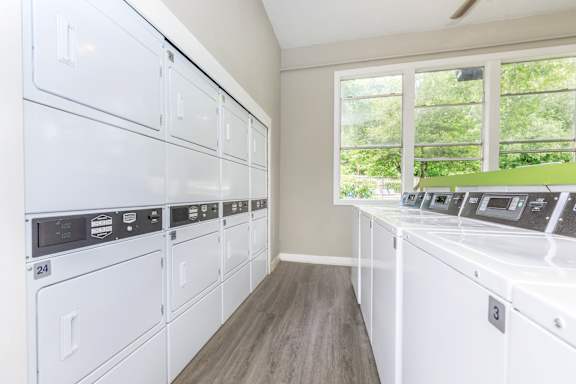 A row of white washing machines in a laundry room.