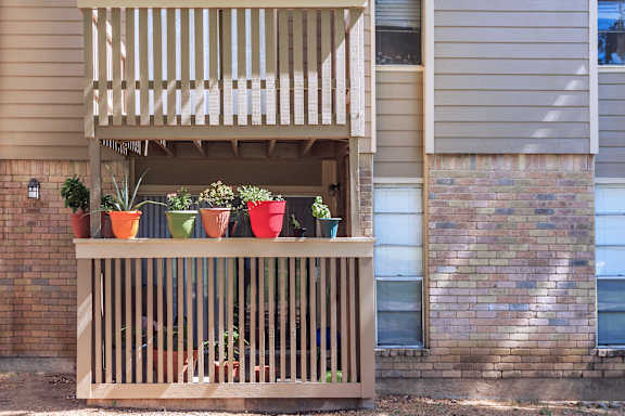 A balcony with a wooden railing and several potted plants.