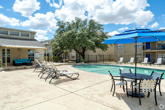 A pool area with chairs and a table.