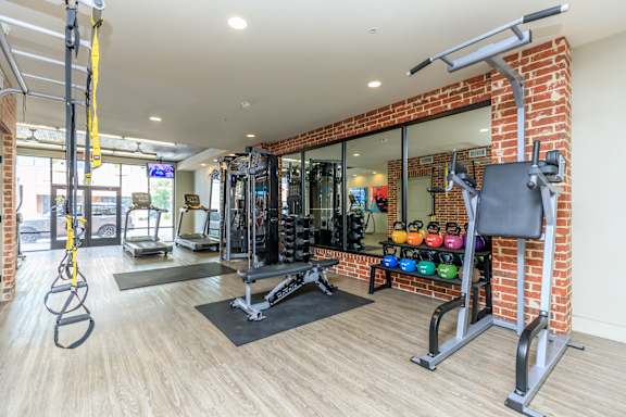 A gym with a variety of equipment including a squat rack, bench, and weights.