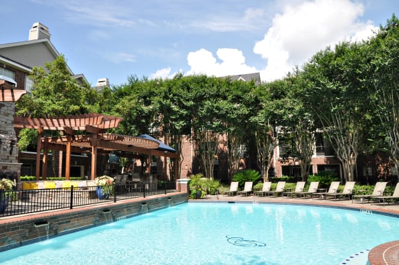 a swimming pool in front of a hotel with trees and a building