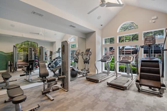 a gym with cardio machines and weights in a building with windows