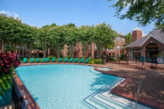 a swimming pool with lounge chairs and a building in the background
