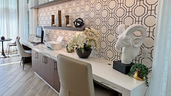 A white desk with a computer and a chair in front of a patterned wall.
