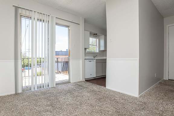 an empty living room with sliding glass doors to a kitchen