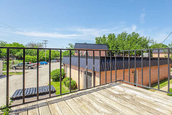 a balcony with a wooden deck and a brick building