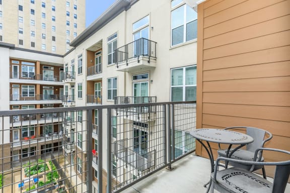 a balcony with a table and chairs and a building in the background