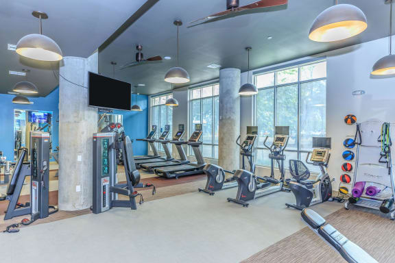 a gym with treadmills and other exercise equipment and windows