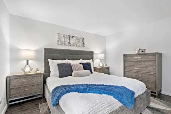 A bedroom with a large bed, two nightstands, and a painting on the wall.