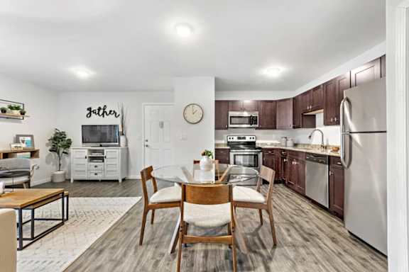 A kitchen with a dining table and chairs in the middle.