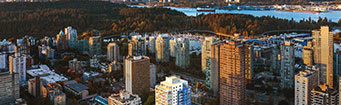 A cityscape with tall buildings and a body of water in the distance.